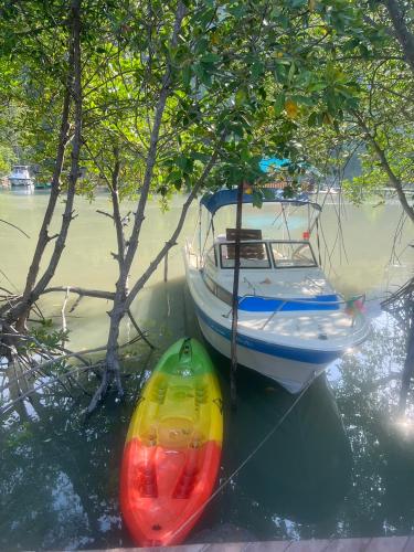 a boat and a canoe in the water next to trees at บ้านพักชายคลอง @บางปู สามร้อยยอด in Ban Bang Pu