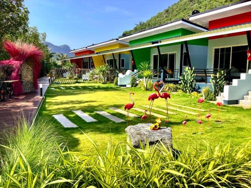 a yard with flamingos in front of a house at บ้านพักชายคลอง @บางปู สามร้อยยอด in Ban Bang Pu