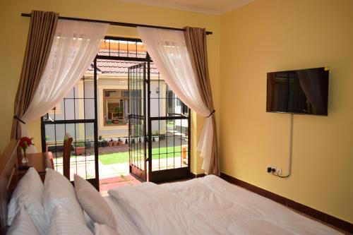 - une chambre avec un lit et une grande fenêtre dans l'établissement Tongas place, à Arusha