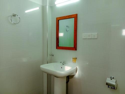 a white bathroom with a sink and a mirror at Sigiriya Peacock Homestay in Sigiriya