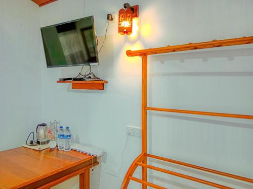 a bedroom with a desk and a television on the wall at Sigiriya Peacock Homestay in Sigiriya