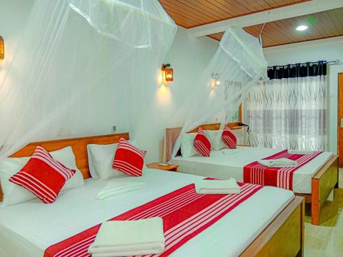 a bedroom with two beds with red and white pillows at Sigiriya Peacock Homestay in Sigiriya