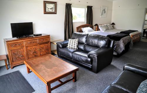 a living room with a couch and a bed at Catnap Cottage, Manapouri in Manapouri
