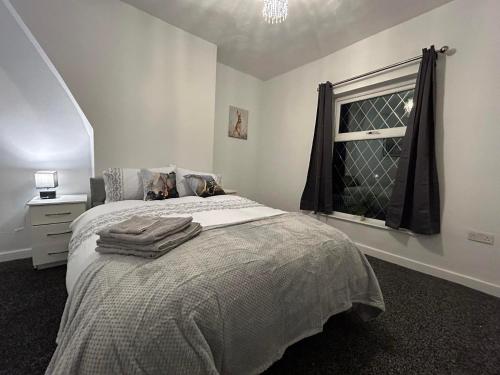 a white bedroom with a bed with a window at Comfortable, spacious 2 Bedroom house close to Etihad Stadium in Stalybridge