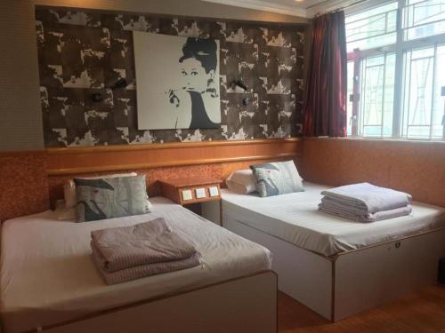 Duas camas individuais num quarto com uma fotografia na parede em New Fortunate Guest House A1 em Hong Kong