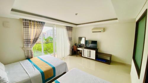May Hotel Sonasea Phu Quoc في فو كووك: غرفة نوم مع سرير وبلكونة مع تلفزيون