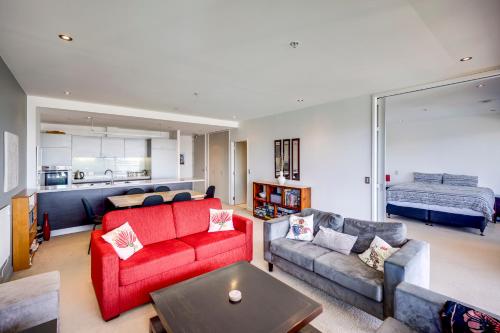 a living room with a red couch and a table at The Bay Bach - Napier Holiday Apartment in Napier