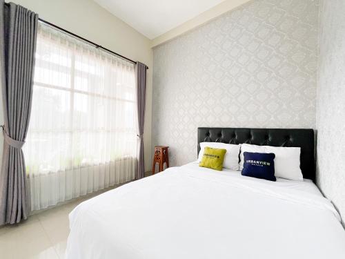 a bedroom with a white bed with two pillows at Urbanview Syariah Hotel Kanigara Batu in Batu