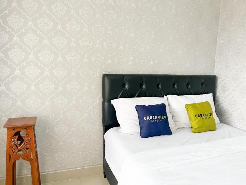 a bedroom with a bed with a black headboard and two pillows at Urbanview Syariah Hotel Kanigara Batu in Batu