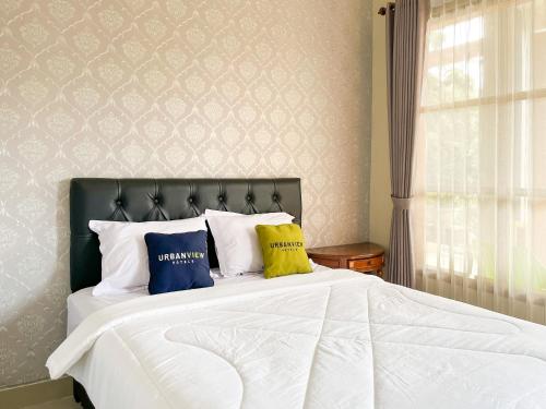 a bedroom with a large white bed with two pillows at Urbanview Syariah Hotel Kanigara Batu in Batu