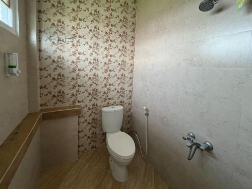 a bathroom with a toilet and a bath tub at Urbanview Syariah Hotel Kanigara Batu in Batu