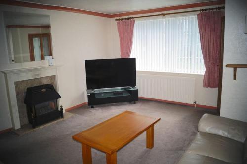 a living room with a flat screen tv and a coffee table at 3 Bed House with Exceptional view in Batley