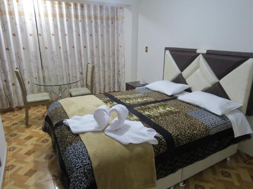 two swans sitting on a bed in a bedroom at Hospedaje EL RINCONCITO II - Cerca al Aeropuerto Jauja in Jauja