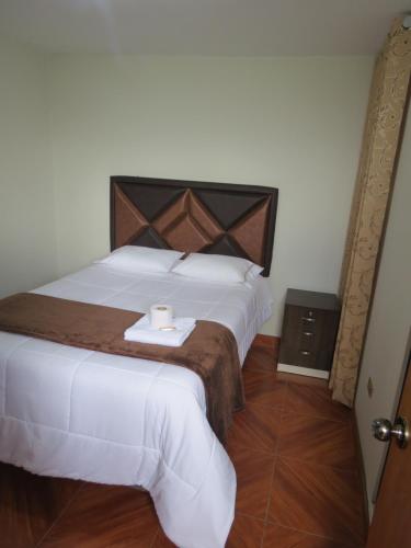 a bedroom with a large white bed with a candle on it at Hospedaje EL RINCONCITO II - Cerca al Aeropuerto Jauja in Jauja