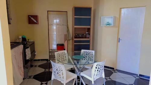 uma sala de jantar com uma mesa de vidro e cadeiras brancas em Riverside house em Barra dos Coqueiros