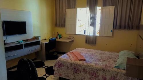 Schlafzimmer mit einem Bett, einem Schreibtisch und einem TV in der Unterkunft Riverside house in Barra dos Coqueiros
