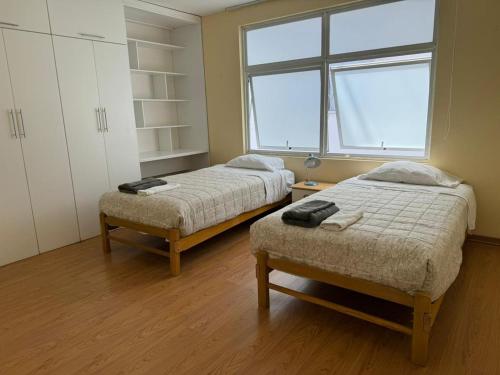 2 camas en una habitación pequeña con ventana en Apartamento Florentino 201, en Lima