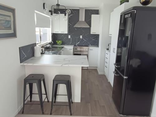 a kitchen with white counters and a black refrigerator at Omanu Cottage in Mount Maunganui