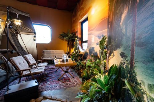 De Vivre Homestay Măng Đen في Kon Von Kla: غرفة معيشة فيها نباتات وطاولة وكراسي