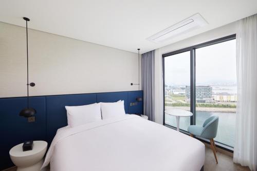 ein Schlafzimmer mit einem großen Bett und einem großen Fenster in der Unterkunft Citadines Connect Hari Busan in Busan