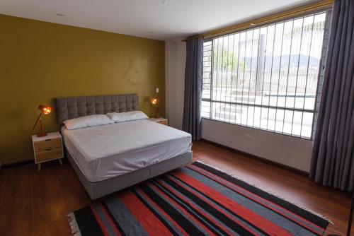 a bedroom with a bed and a large window at Mirador Departamento in Loja