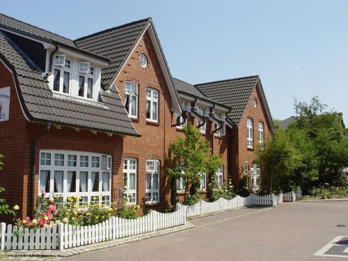 a row of brick houses with a white fence at Seeblick Genuss und Spa Resort Amrum in Norddorf
