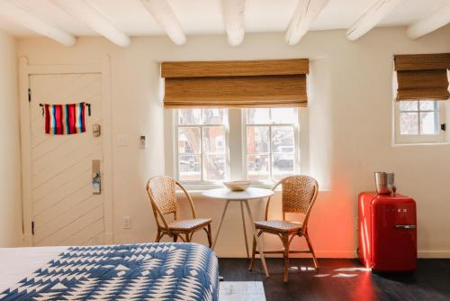 a bedroom with a table and chairs and a red suitcase at Pueblo Bonito Inn in Santa Fe