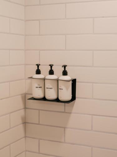three bottles of soap sitting on a shelf in a bathroom at Pueblo Bonito Inn in Santa Fe