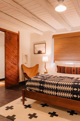 a bedroom with a bed and a chair in a room at Pueblo Bonito Inn in Santa Fe