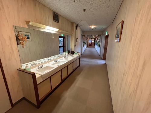 La salle de bains est pourvue de 3 lavabos et d'un miroir. dans l'établissement Tomiya Ryokan, à Myōkō