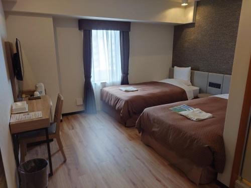 a hotel room with two beds and a desk at Hotel Southern Coast Miyakojima in Miyako-jima