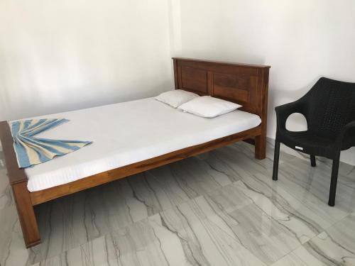 a bed with a wooden frame and a chair at Black and White Rest in Kurunegala
