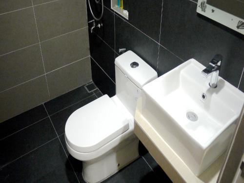 a bathroom with a white toilet and a sink at RG Grand Hotel in Parit Raja