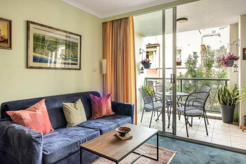 a living room with a blue couch and a table at Charming Chippendale Escape with Rooftop Pool in Sydney