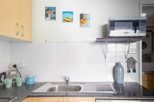 a kitchen counter with a sink and a microwave at Charming Chippendale Escape with Rooftop Pool in Sydney