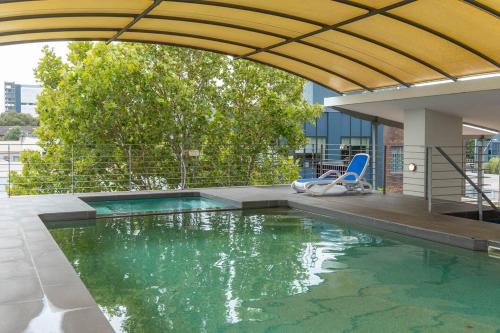 a swimming pool with a blue chair and a swimming pool at Charming Chippendale Escape with Rooftop Pool in Sydney