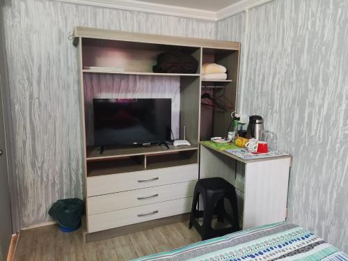 a bedroom with a entertainment center with a flat screen tv at RdA Habitación para dos in Pichilemu