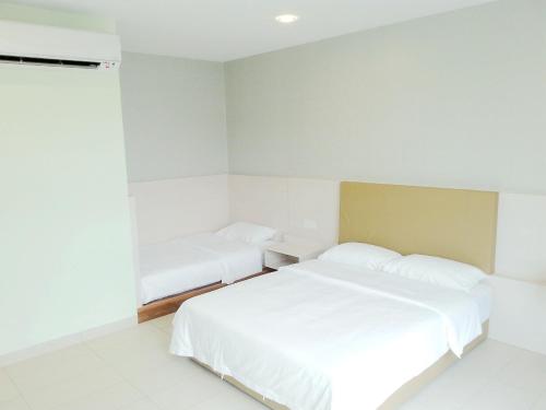 a white bedroom with two beds and a window at RG Grand Hotel in Parit Raja