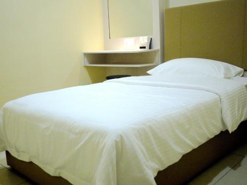 a large white bed in a room with at RG Grand Hotel in Parit Raja