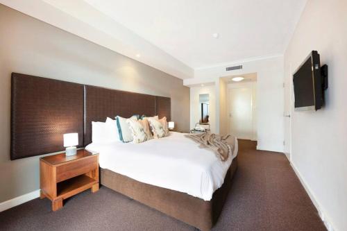 a bedroom with a large bed and a television at Elegant Harbourside Comfort with Alfresco Patio in Darwin