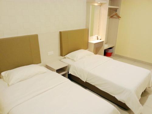 two beds in a small room with white sheets at RG Grand Hotel in Parit Raja