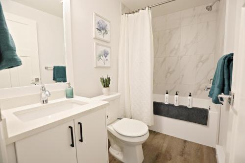 a white bathroom with a sink and a toilet at Queen Suite 20 Min from YEG Airport with Disney in Edmonton