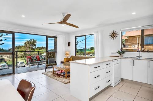 a kitchen with white cabinets and a living room at Lou's Tiki Pad in Gold Coast