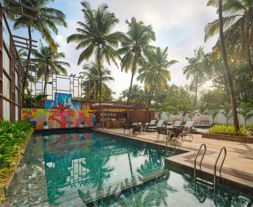 een zwembad in een resort met palmbomen bij Moyrah By Greenpark in Anjuna