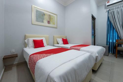 two beds in a hotel room with red and white sheets at Sg Rengit City Resort 2 in Kampung Sungai Rengit