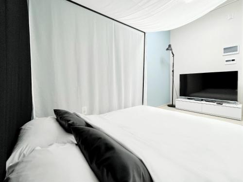 a white bed with black pillows and a television at Landmark Stay in Songdo in Incheon