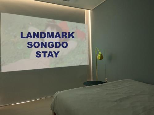 a poster on a wall in a room with a bed at Landmark Stay in Songdo in Incheon