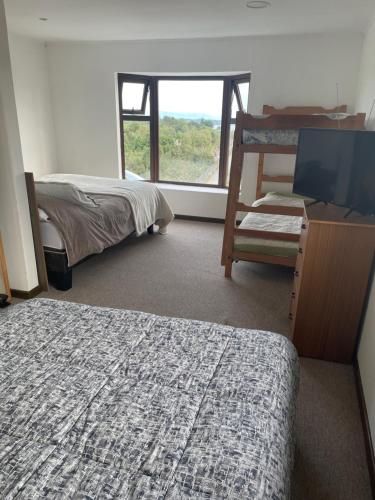a bedroom with two beds and a tv and a window at Casa Sra Oti, Tipo Hostal con vista al mar Puerto Montt - CHINQUIHUE in Puerto Montt
