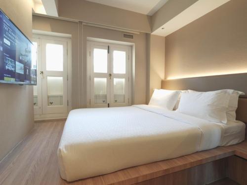 a large white bed in a room with a tv at Hotel 1900 Express Chinatown in Singapore