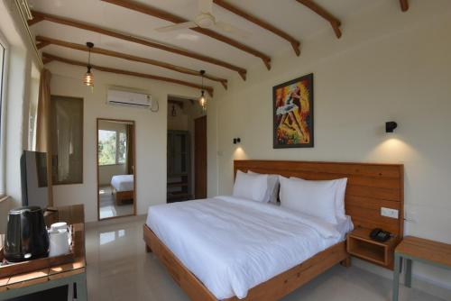 a bedroom with a large bed with white sheets at Ekawa Ganga by Lawrence Hotels in Rishīkesh